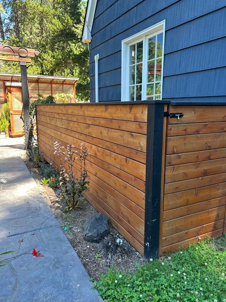 Horizontal cedar fence with black posts beside a blue house